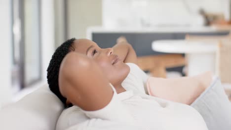 Happy-african-american-woman-sitting-on-sofa-and-relaxing,-slow-motion