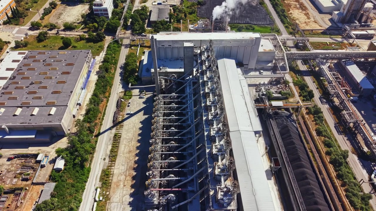 Vista di un grande impianto industriale situato in un'area urbana con diversi edifici e attrezzature durante il giorno.