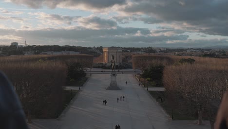 revealing shot of two young male mesmerized by arc de triomphe golden hours view