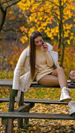 cheerful cute woman phoning and resting in park. pretty young lady having a phone call in park. vertical video