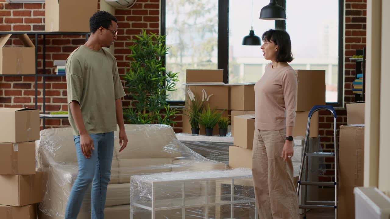 Multiethnic partners carrying table in new rented home