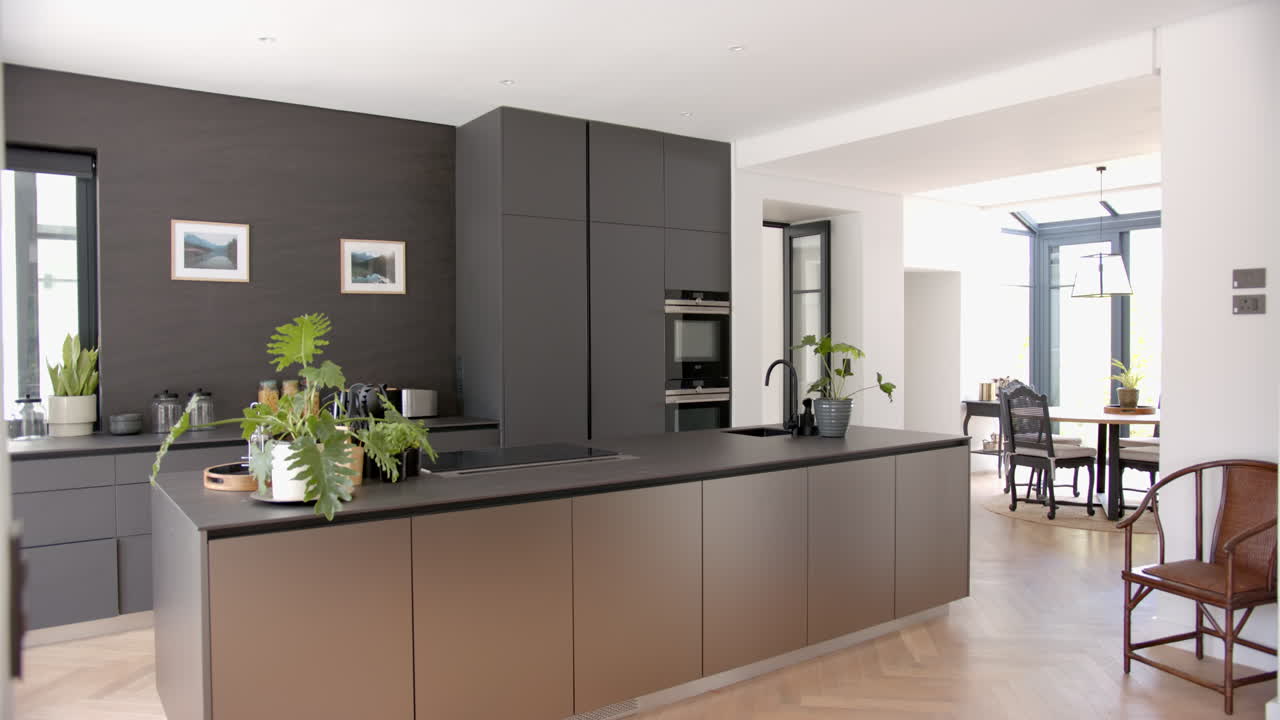 A modern kitchen features sleek dark cabinetry and a central island ...