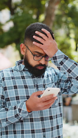 surprised indian man use smartphone loses bad news fortune loss fail outdoors in city street