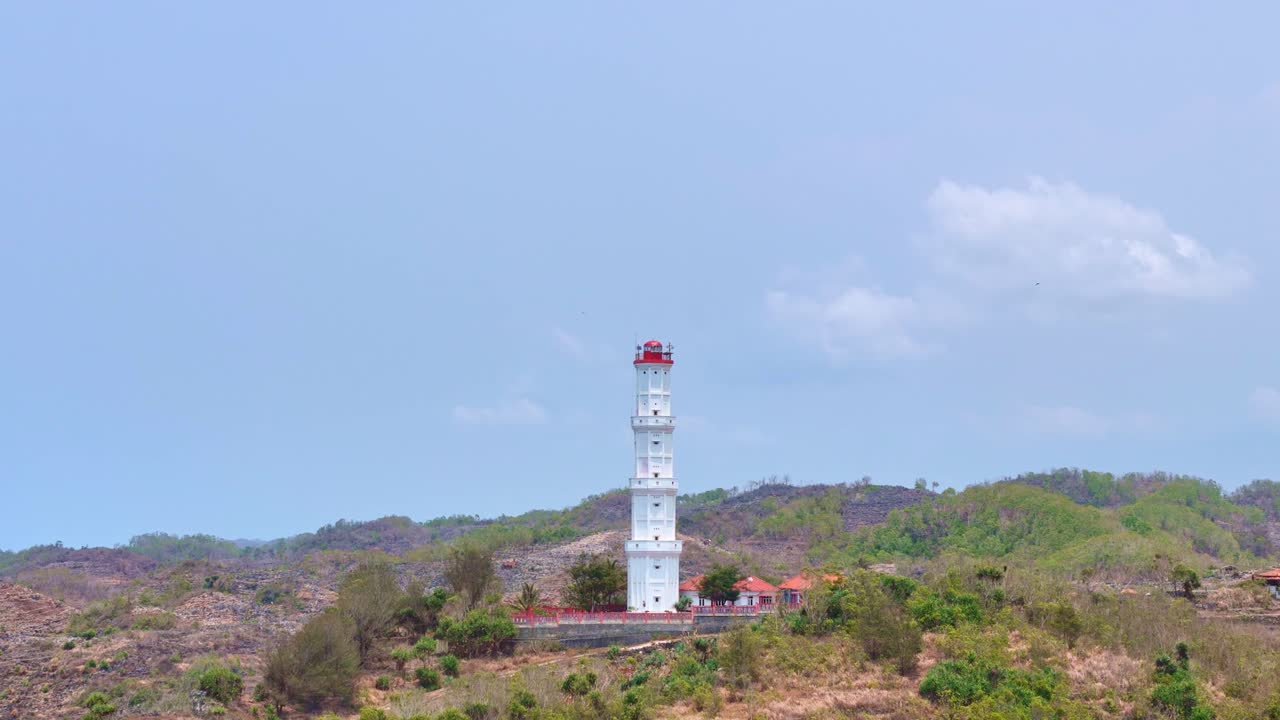 White lighthouse near Baron beach in Indonesia, aerial fly backward view