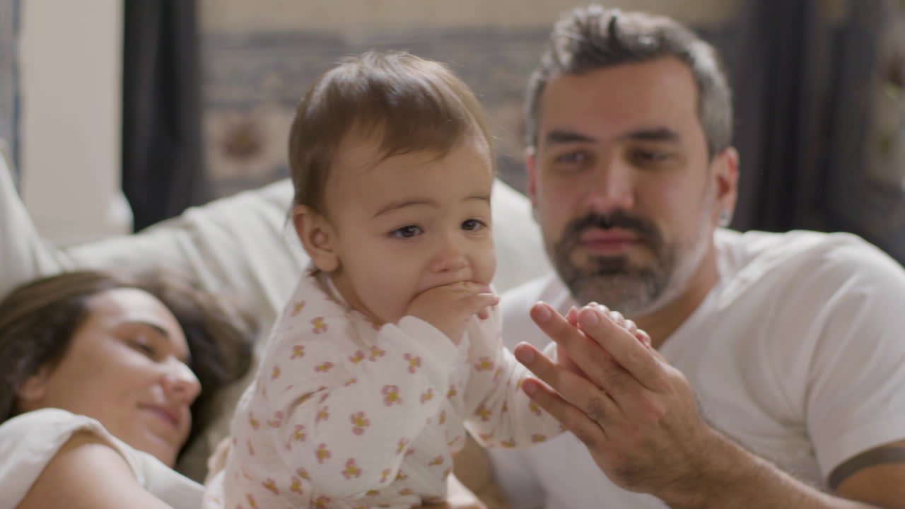 일요일 아침에 침대에 누워 귀여운 딸과 놀고 있는 행복한 커플 5