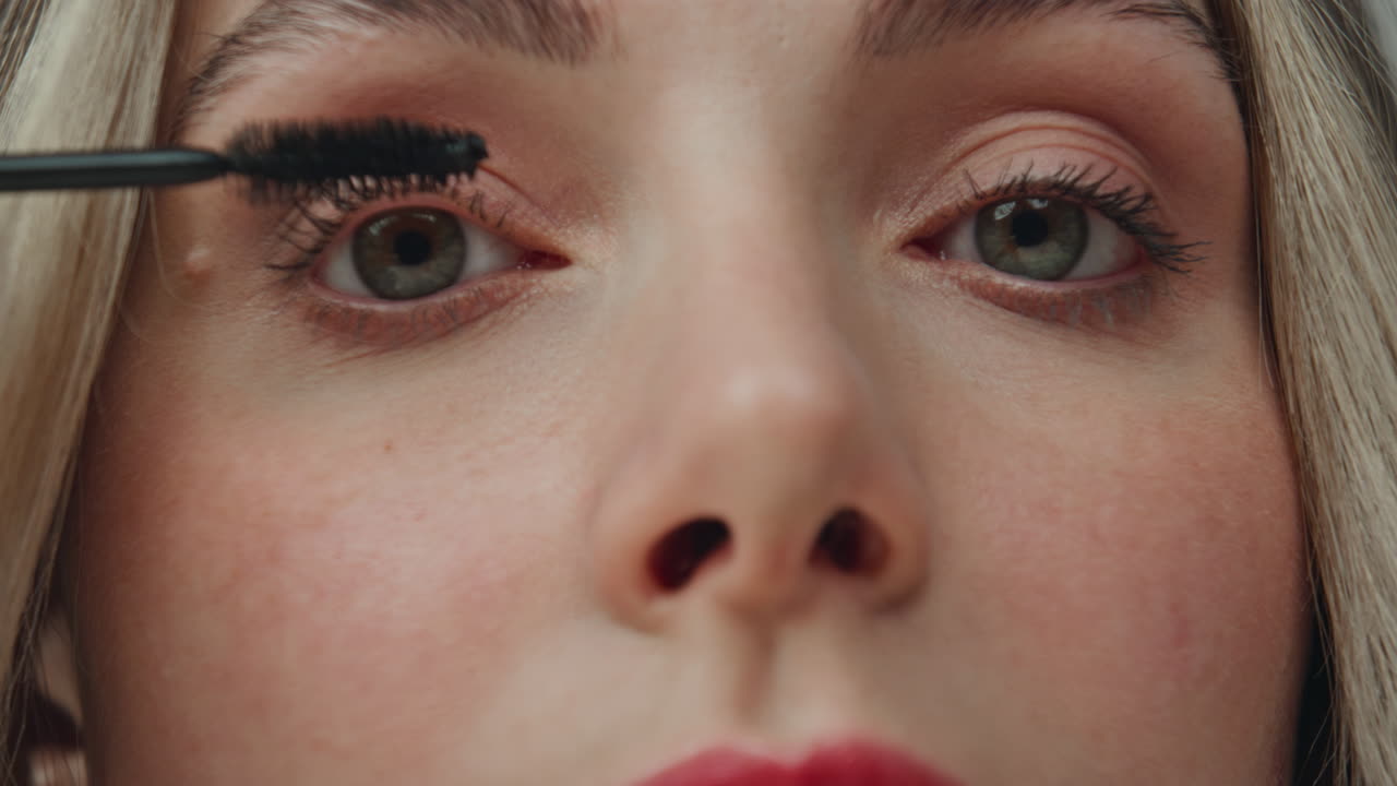 mujer que aplica el rimel en sus pestañas