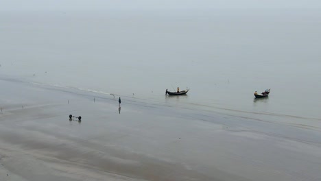 kuakata beach, bangladesh - fishing boats departing from the coastline amidst the monsoon season - wide shot