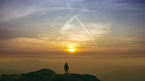 el hombre de pie en una montaña en un brillante fondo de puesta de sol