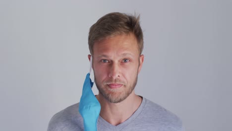 retrato de un hombre caucásico con una máscara facial azul y una camiseta gris