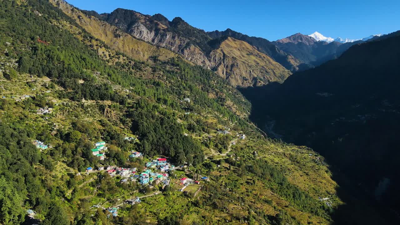 una toma aérea de un dron que destaca un pueblo aislado con casas tradicionales en medio del vibrante paisaje verde.