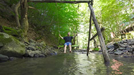 the young man swinging on the swing in the creek.