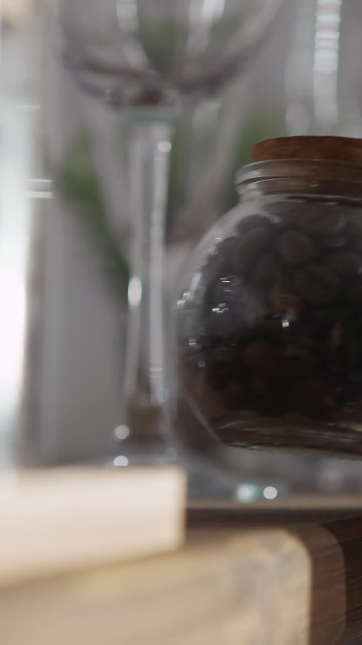 una mujer toma café del estante de la cocina. una mujer alcanza un frasco de vidrio lleno de granos de café aromáticos en un estante de madera. preparación de bebidas calientes