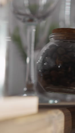 una mujer toma café del estante de la cocina. una mujer alcanza un frasco de vidrio lleno de granos de café aromáticos en un estante de madera. preparación de bebidas calientes