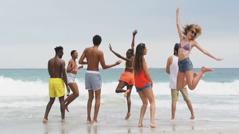 group of mixed-race friends dancing together on the beach 4k