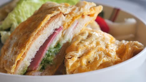 close-up of a delicious breakfast sandwich with egg, ham, and pesto