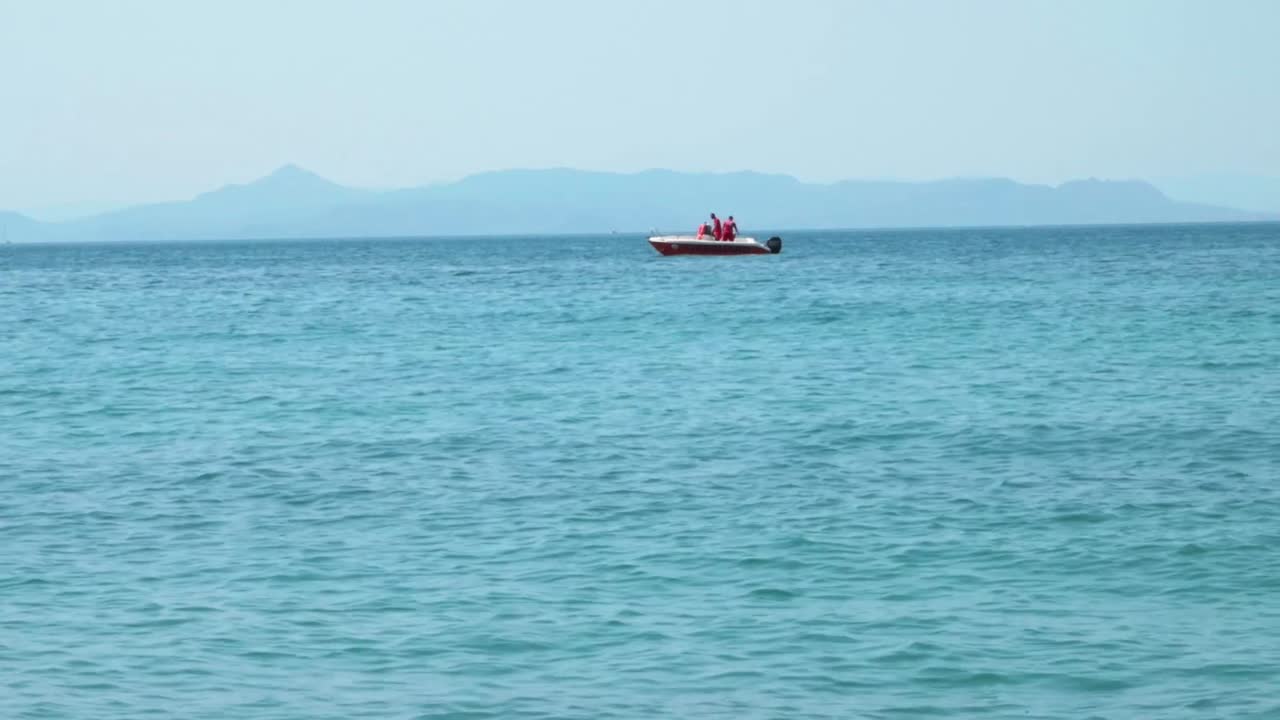 배경에 산이 있는 밝은 푸른 바다의 작은 모터 보트