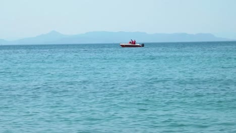 small motor boat on light blue sea with mountains in the background