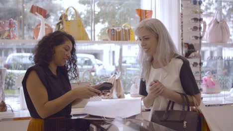 cheerful satisfied fashion store customer paying for purchase and talking with shop assistant