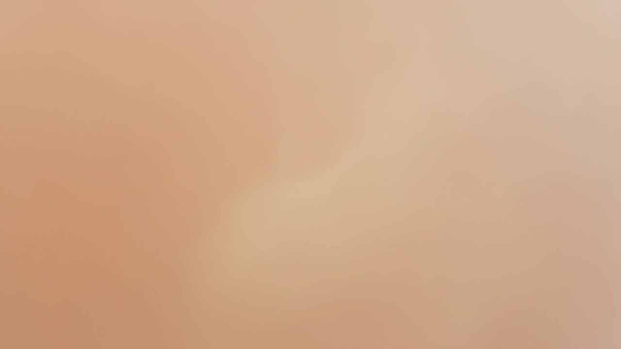 Verschwommene beige Oberfläche verschiebt sich an unbekanntem Ort, während Kamera Fokus und Helligkeit anpasst.