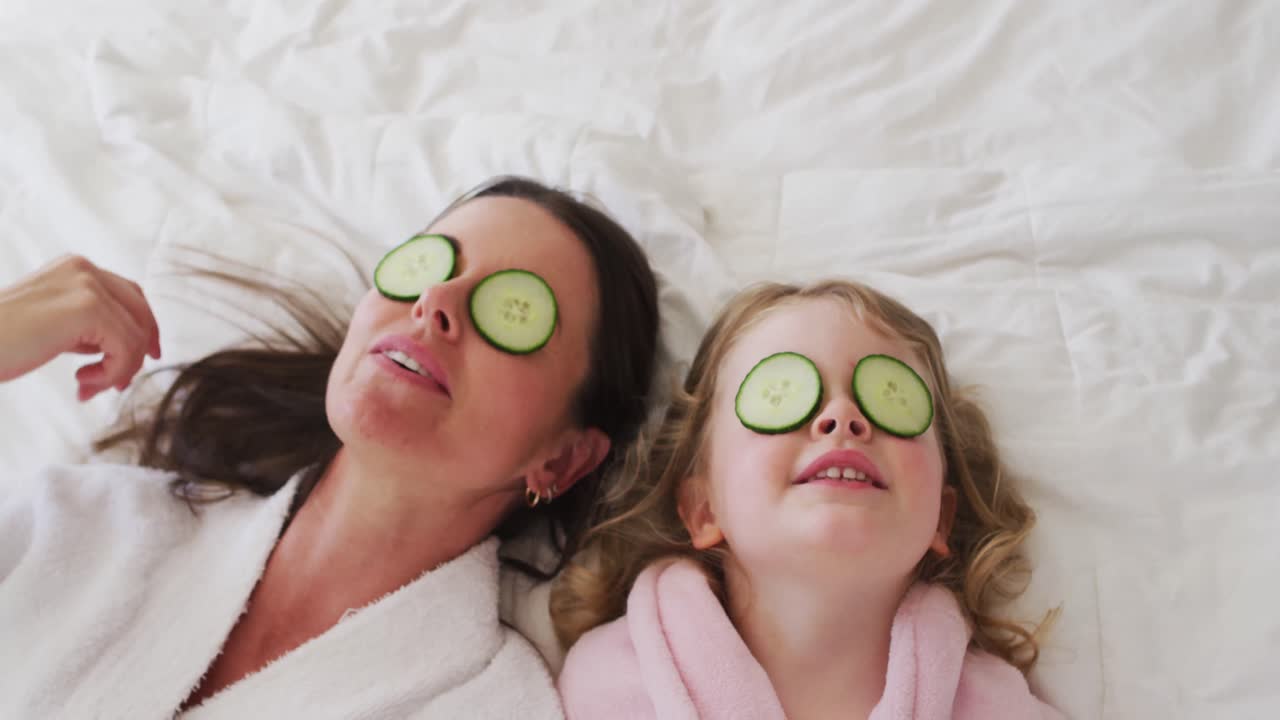 Caucasian mother and daughter having fun in bedroom