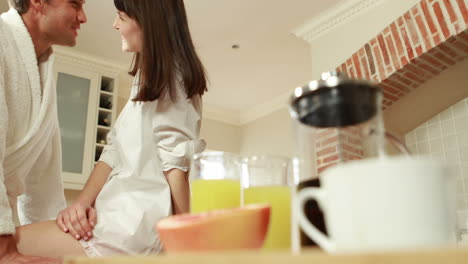 una pareja feliz hablando en la cocina.