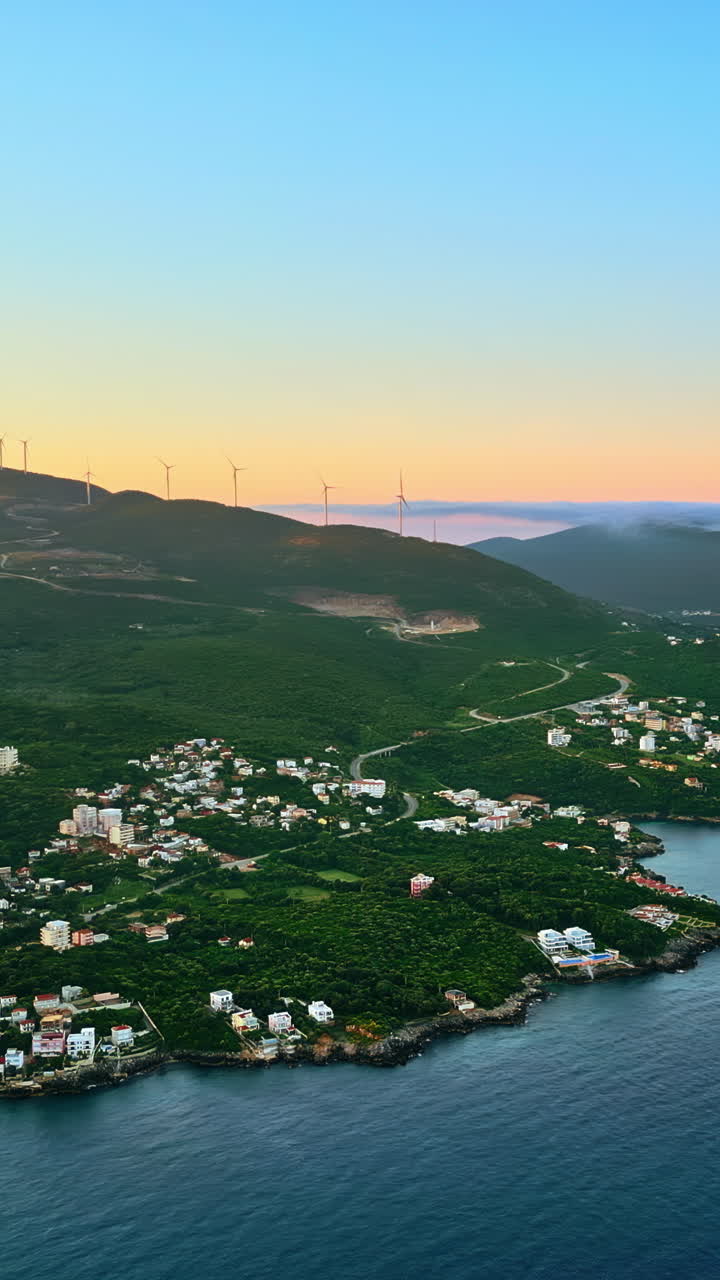 Aerial, drone view of buildings on the shore of the Adriatic sea, with mountains on the background in Montenegro at sunset. Vertical