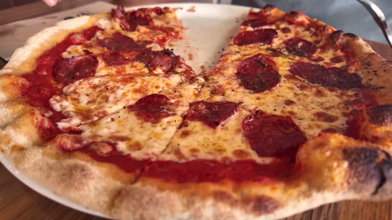 Vista ravvicinata delle mani di un uomo caucasico che mangia una pizza al salame piccante usando forchetta e coltello. Timelapse