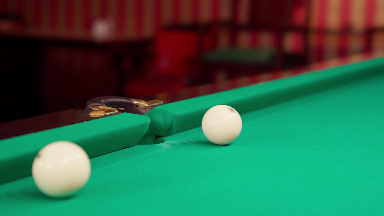 Witte biljartbal zinkt in de pocket op een groene tafel