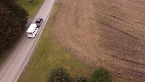 pick up truck hauling white horse trailer through rural michigan landscape