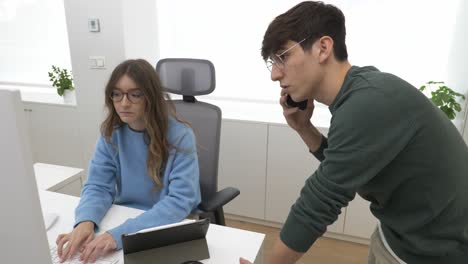 office workers discussing work on phone and computer