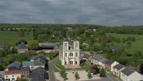 moody, overcast cloudy sky and gothic style church in france surrounded by lush green fields