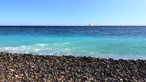 pebble beach in nice france, pebble beach stones with turquoise sea water and blue sky, motion of the water