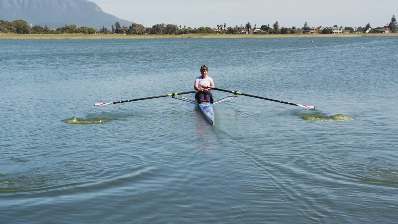 mujer caucásica mayor remando un barco en un río