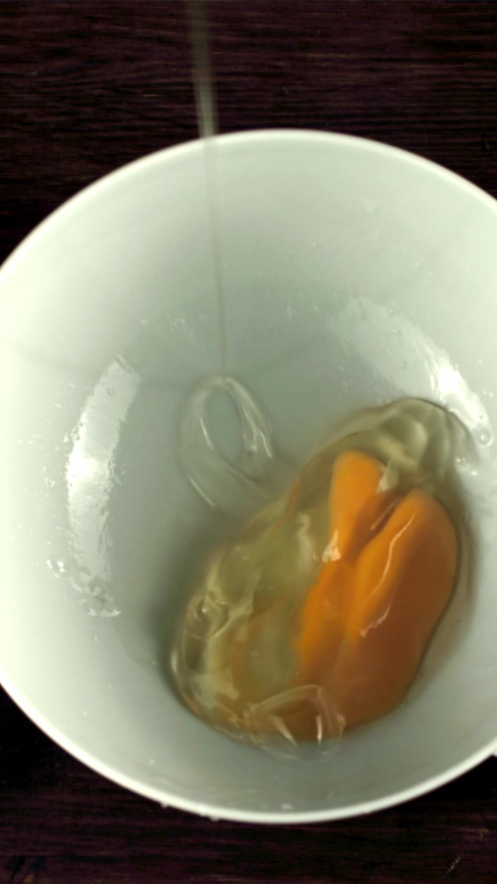 Slow Motion Egg Cracking and Pouring into a White Bowl