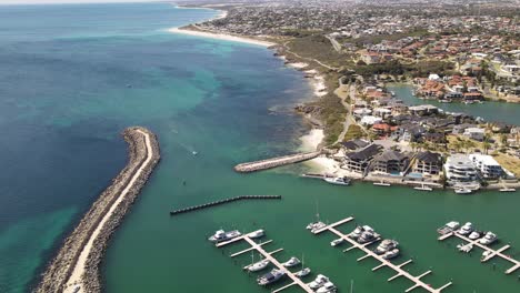 aerial footage of flying over mindarie marine and the pier and boats on a clear summers day