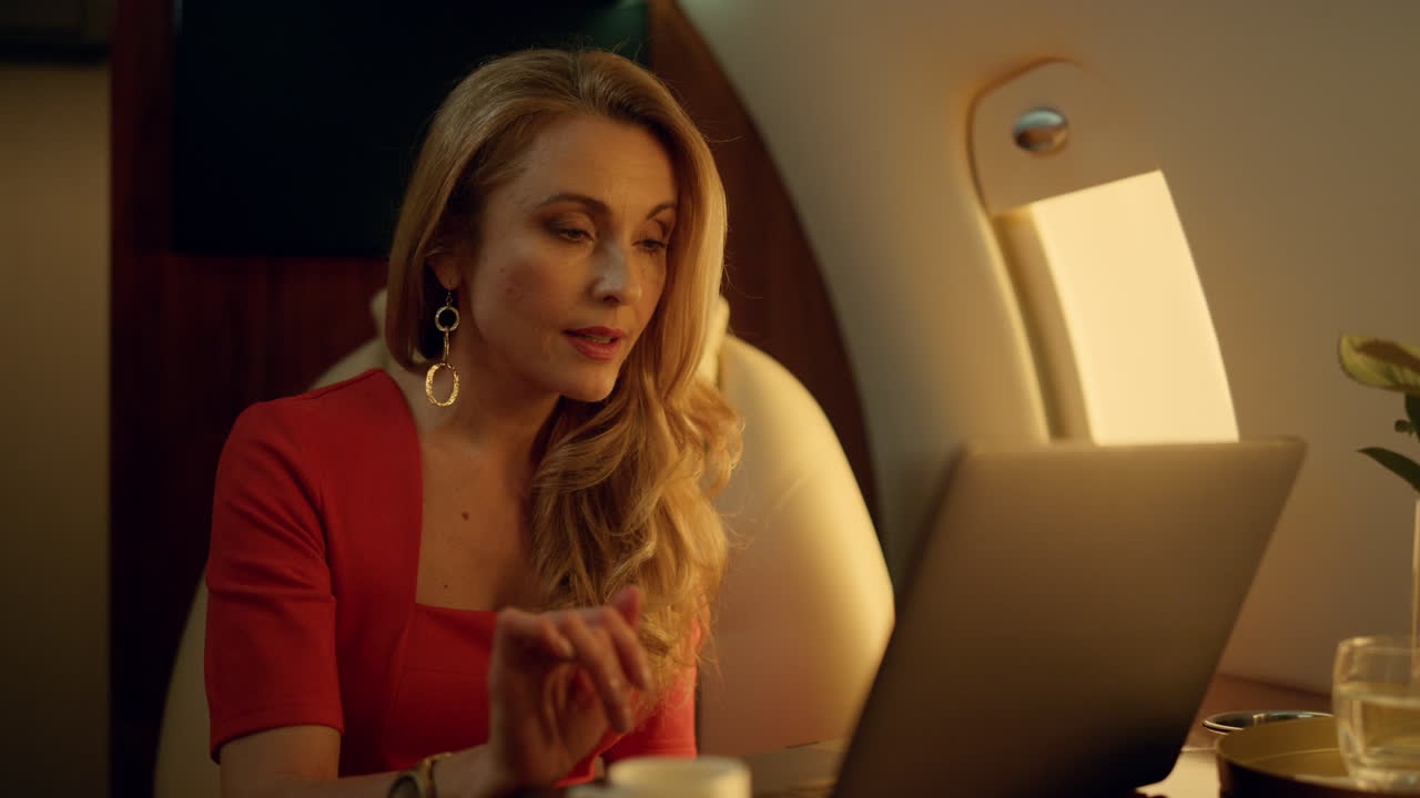 socio de negocios hablando con computadora portátil. mujer elegante trabajando en un avión.