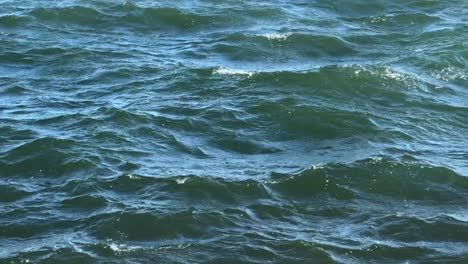 Dynamic-close-up-of-ocean-waves-under-natural-light,-showcasing-the-textured-surface-and-movement-of-the-water