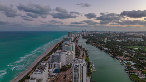 Forwards-fly-above-row-of-tall-buildings-on-seaside.-Hyperlapse-shot-of-hotels-or-apartment-buildings-along-multilane-road-at-dusk.-Miami,-USA