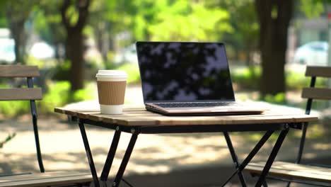 serene outdoor workspace featuring a laptop and coffee on a table surrounded by nature, ideal for remote work and relaxation in a tranquil setting