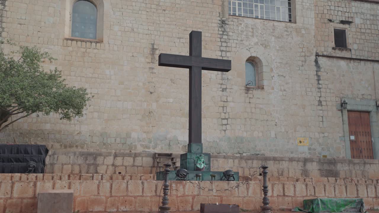 A Cross in front of a Brick Building