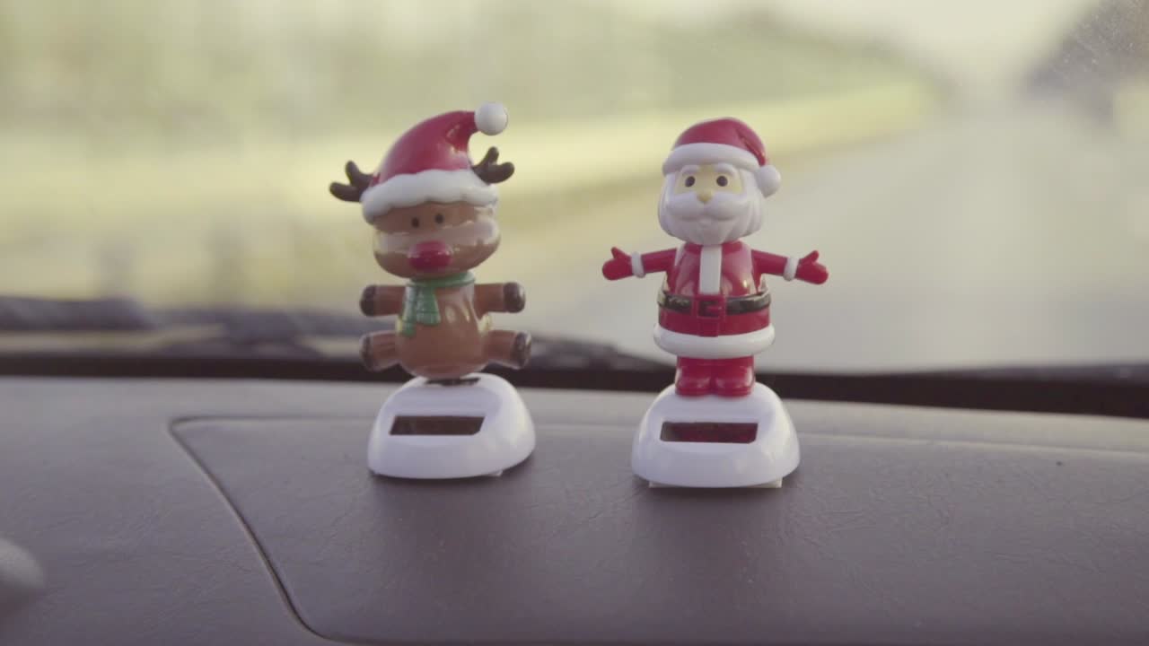 Bambole bobblehead di Babbo Natale e renne sul cruscotto con la scritta "Buon Natale".