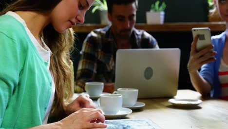 mujer usando una tableta digital mientras toma café