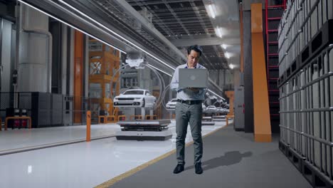 full body of an asian male professional worker standing with his laptop in ev car factory, high-tech industrial facility, he is nodding his head with dissapionted