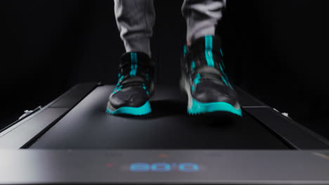 static frontal close up shot of a man's feet running on a treadmill