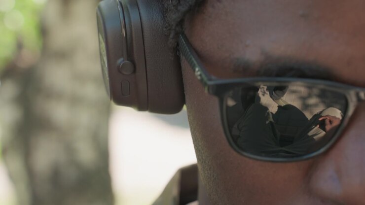 Close up of man wearing sunglasses and ear protection with reflections visible in lenses. subject remains stationary throughout showing consistent details like facial features and protective