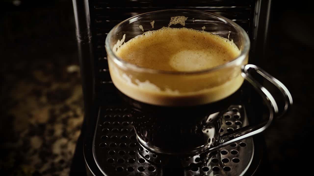 Hand Take The Clear Glass With Freshly Brewed Aromatic Hot Coffee From The Coffee Maker.-  closeup shot