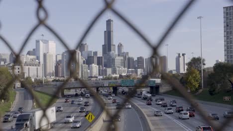 downtown chicago skyline and highway traffic, viewed through a fence in daylight