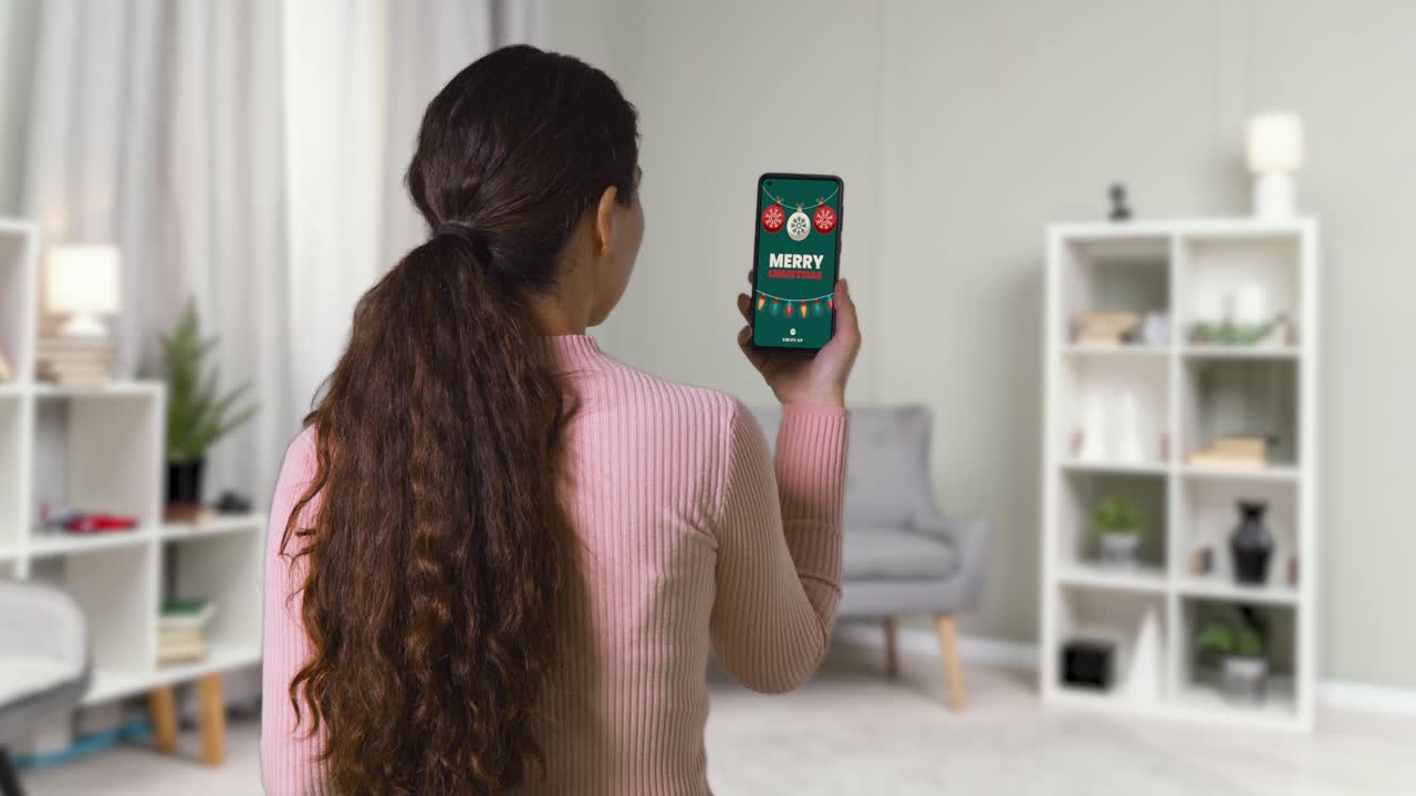 집에 있는 여성이 휴대 전화로 크리스마스 온라인 제안을 보고 있습니다.