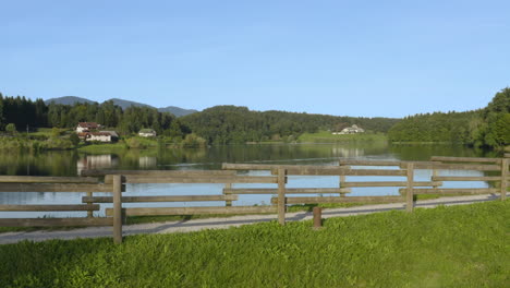 Sideways-scenic-aerial-drone-panorama-view-at-wooden-fence-next-to-lake-on-sunny-autumn-day