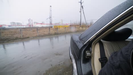 person opening a damaged car door in the rain